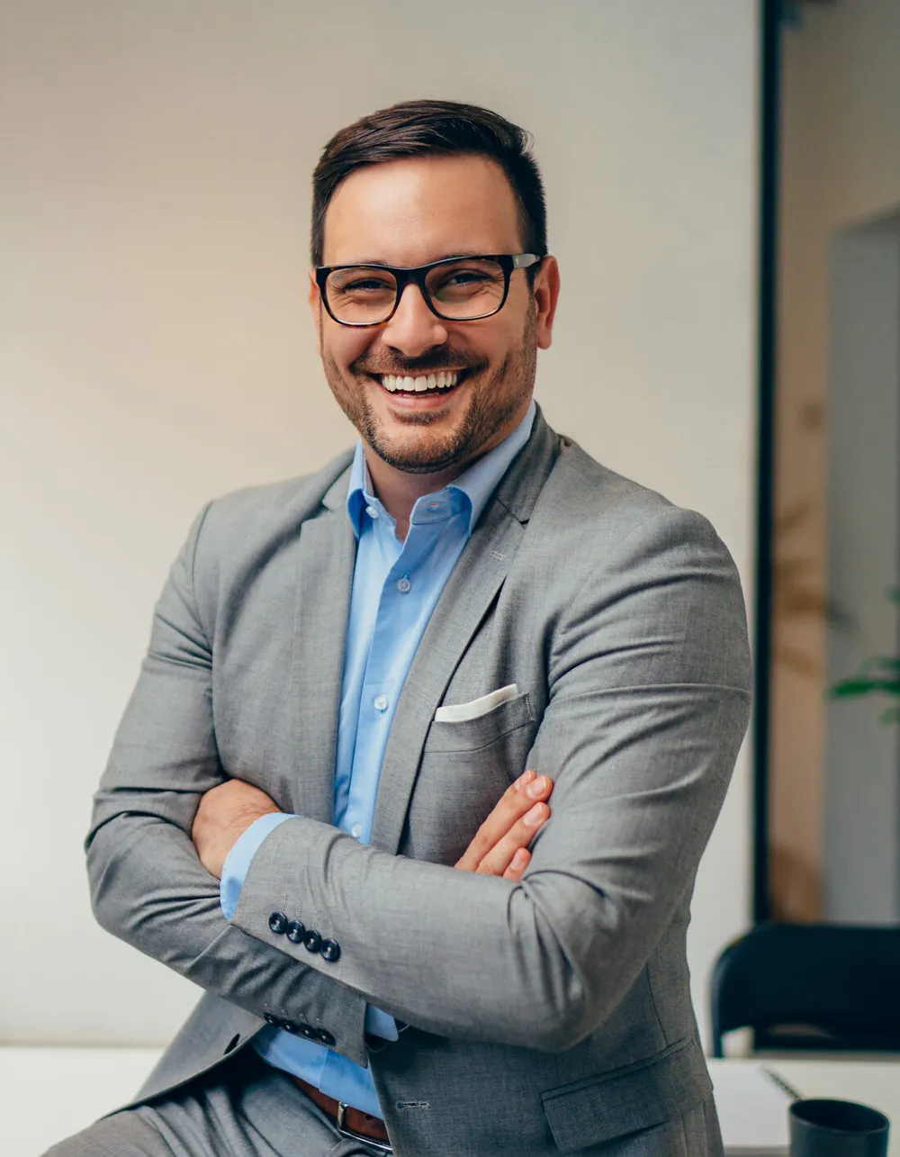 Portrait of young businessman standing in his office with arms crossed Portrait of young businessman standing in his office with arms crossed
